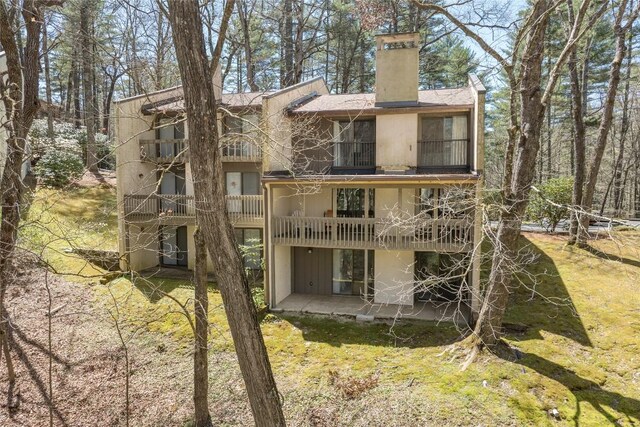 rear view of property with a chimney, a patio area, and a balcony