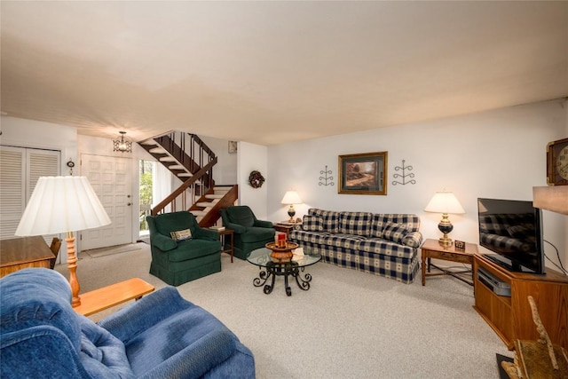 living area with a notable chandelier, stairway, and carpet