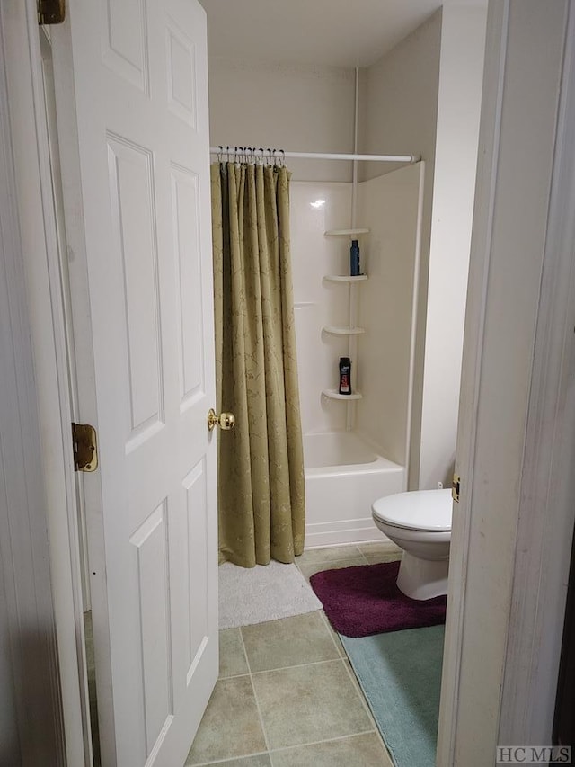 bathroom with shower / bath combination with curtain, tile patterned floors, and toilet