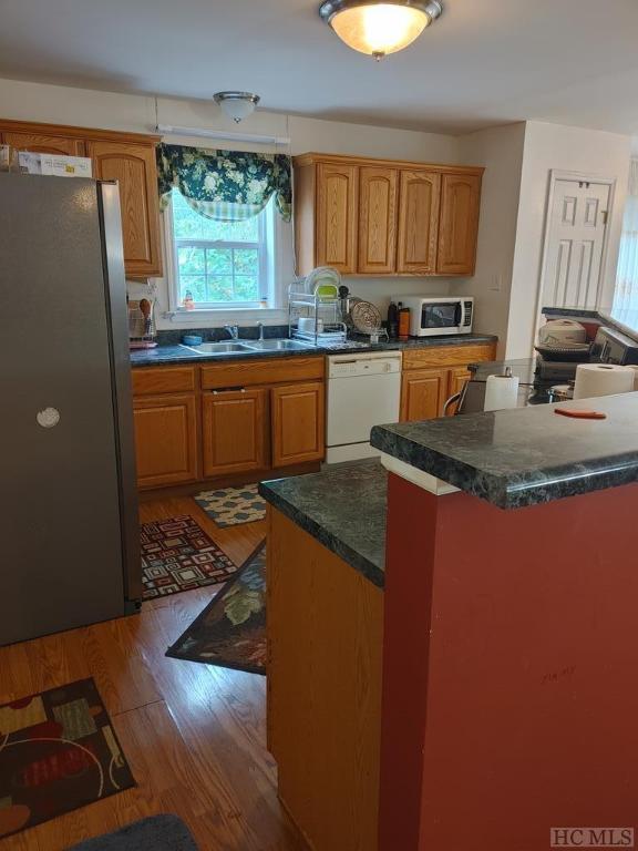 kitchen featuring white appliances, a center island, sink, and hardwood / wood-style floors