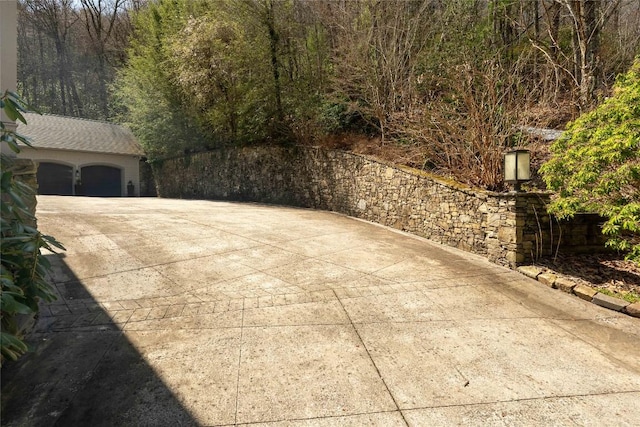 exterior space featuring concrete driveway and a view of trees