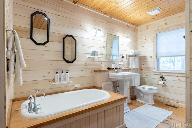 bathroom featuring toilet, wooden walls, a bath, and wood ceiling