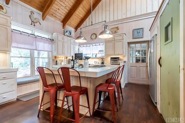 kitchen with beam ceiling, decorative light fixtures, wood ceiling, stainless steel refrigerator, and a center island