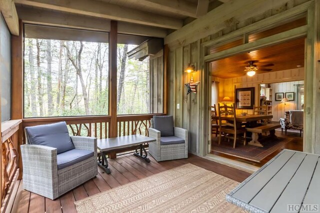 sunroom / solarium featuring ceiling fan and beam ceiling