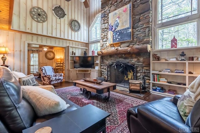 living room featuring ceiling fan, wood walls, and a towering ceiling