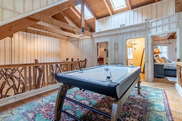 rec room with light hardwood / wood-style flooring, wood walls, wood ceiling, and lofted ceiling with skylight