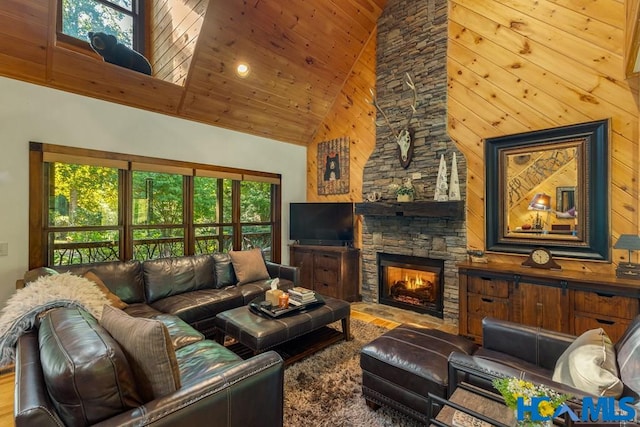 living room with high vaulted ceiling, wooden ceiling, a stone fireplace, and wood finished floors