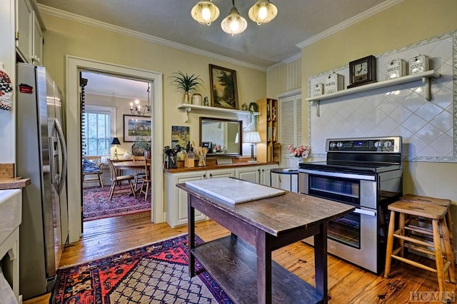 kitchen featuring pendant lighting, crown molding, light hardwood / wood-style flooring, appliances with stainless steel finishes, and an inviting chandelier