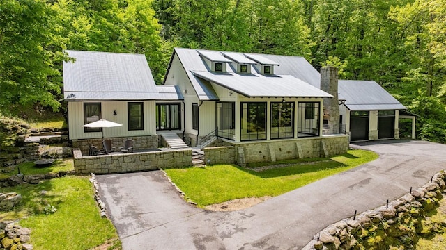 67 Chimney Overlook Dr, Scaly Mountain, NC 28775 - modern inspired farmhouse with driveway, a chimney, metal roof, a view of trees, and a front lawn