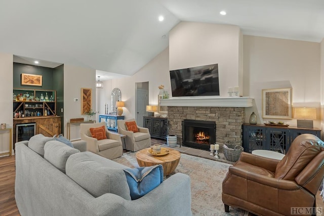 living room with lofted ceiling, bar, wine cooler, a fireplace, and light wood-type flooring