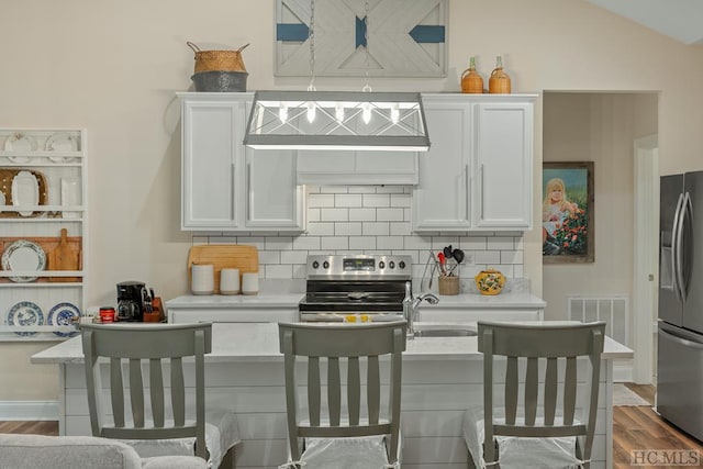 kitchen with stainless steel appliances, backsplash, white cabinets, and light stone counters