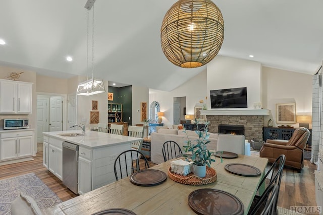 dining room with high vaulted ceiling, a fireplace, light hardwood / wood-style floors, and sink