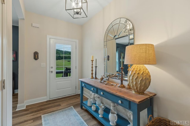 entryway featuring dark wood-type flooring and a chandelier