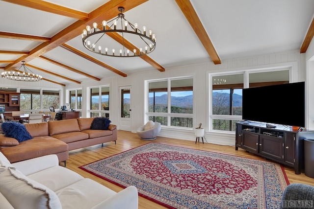 living room with light hardwood / wood-style floors, plenty of natural light, lofted ceiling with beams, and a notable chandelier