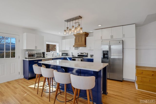 kitchen featuring appliances with stainless steel finishes, white cabinets, a center island, and pendant lighting