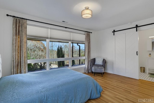 bedroom featuring a barn door and wood-type flooring