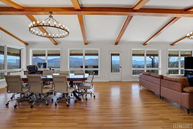 dining room featuring a notable chandelier, light hardwood / wood-style flooring, vaulted ceiling with beams, and a mountain view