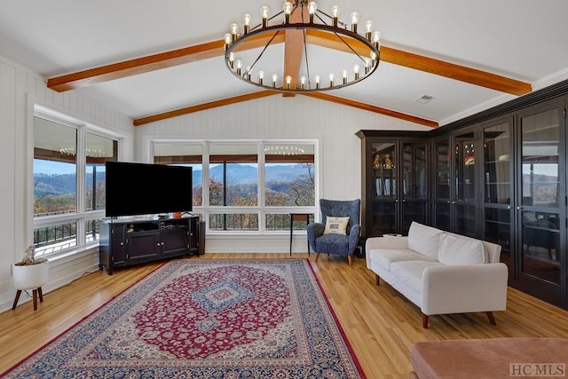 living room with lofted ceiling with beams, an inviting chandelier, and light hardwood / wood-style floors