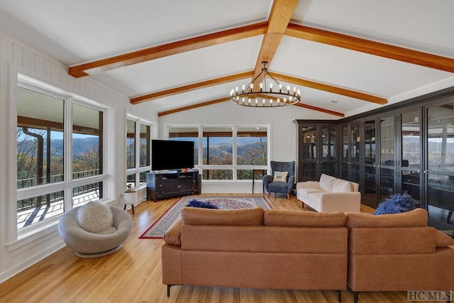 living room with a notable chandelier, light hardwood / wood-style flooring, vaulted ceiling with beams, and a healthy amount of sunlight