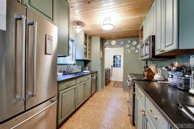 kitchen featuring appliances with stainless steel finishes, sink, wooden ceiling, and washer and clothes dryer