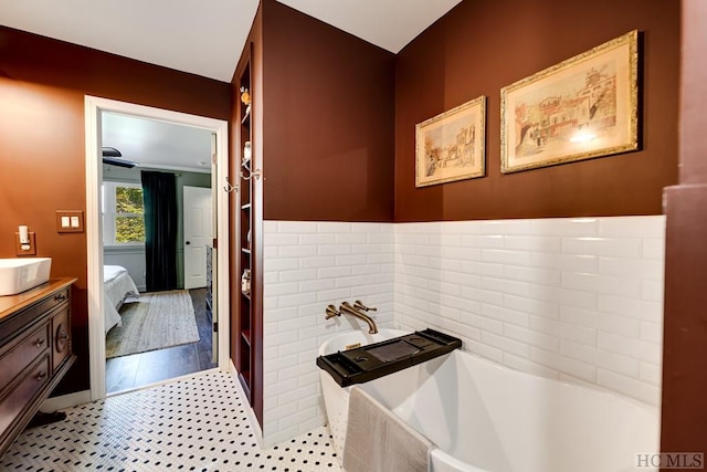 bathroom featuring tiled tub, vanity, and tile patterned floors