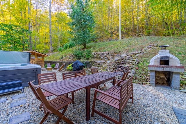 view of patio with a hot tub and an outdoor fireplace