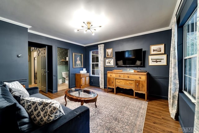 living room with crown molding, wood-type flooring, an inviting chandelier, and a baseboard heating unit