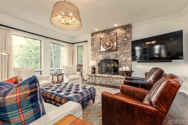 living room with crown molding, a stone fireplace, hardwood / wood-style floors, and a notable chandelier