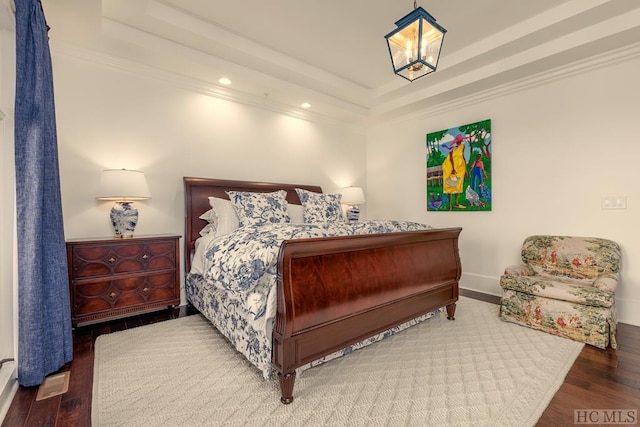 bedroom featuring crown molding, hardwood / wood-style flooring, and a raised ceiling