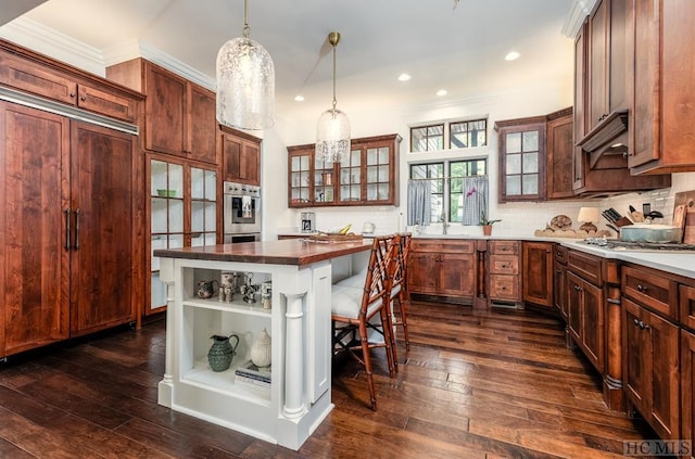 kitchen featuring pendant lighting, a kitchen bar, a center island, and dark wood-type flooring