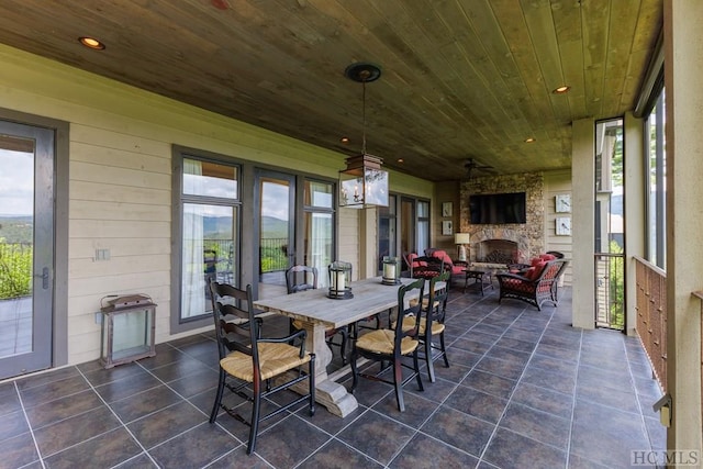 sunroom featuring wooden ceiling and an outdoor stone fireplace