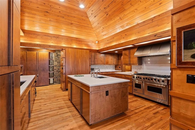 749 Stillmont Cir, Cashiers, NC 28717 - kitchen featuring range with two ovens, brown cabinetry, a sink, wall chimney exhaust hood, and an island with sink