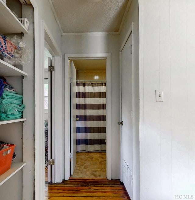 hall with dark hardwood / wood-style flooring, ornamental molding, and a textured ceiling