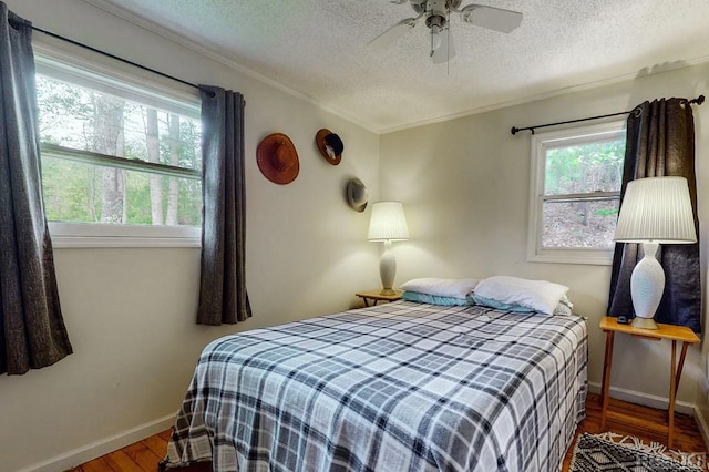 bedroom with a textured ceiling, hardwood / wood-style floors, crown molding, and ceiling fan