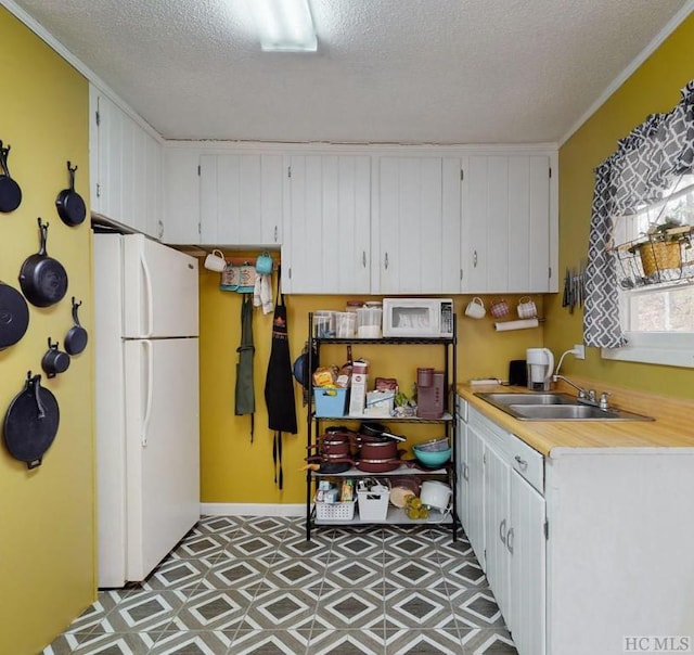 kitchen with sink, ornamental molding, white appliances, a textured ceiling, and white cabinets