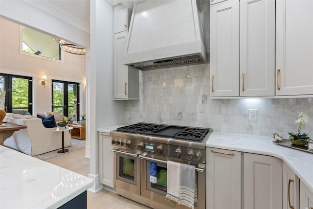227 Sherwood Forest Rd, Highlands, NC 28741 - kitchen featuring custom exhaust hood, double oven range, open floor plan, decorative backsplash, and light stone countertops