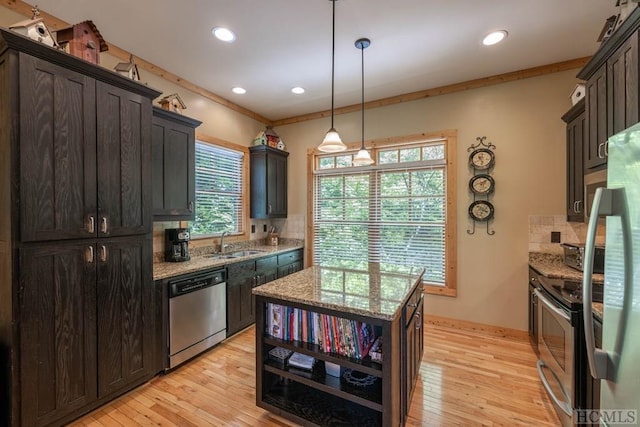 kitchen featuring light stone countertops, hanging light fixtures, stainless steel appliances, and dark brown cabinets