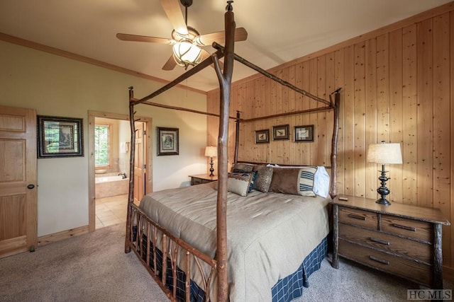 carpeted bedroom with ceiling fan, crown molding, ensuite bath, and wooden walls