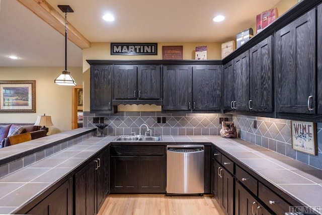 kitchen with decorative light fixtures, sink, stainless steel dishwasher, and tile countertops