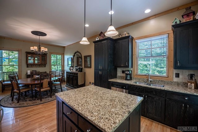 kitchen featuring tasteful backsplash, dishwasher, sink, a kitchen island, and decorative light fixtures