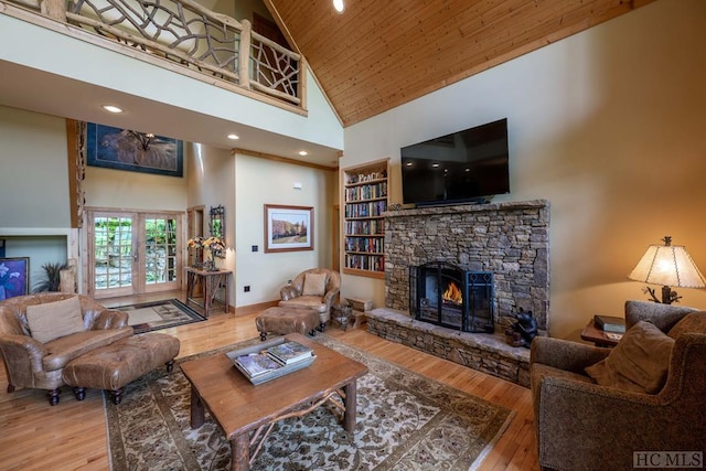 living room featuring french doors, a stone fireplace, hardwood / wood-style flooring, high vaulted ceiling, and wooden ceiling