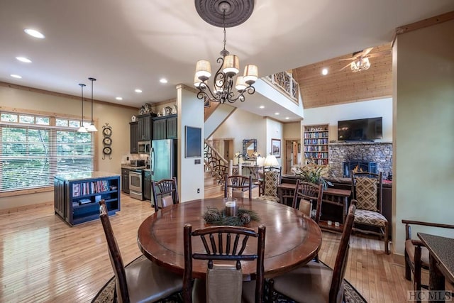 dining area featuring ceiling fan with notable chandelier, light hardwood / wood-style floors, and a fireplace