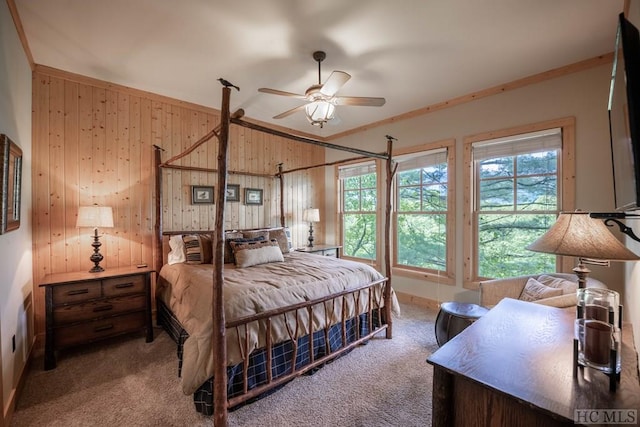 bedroom with crown molding, wooden walls, ceiling fan, and carpet floors