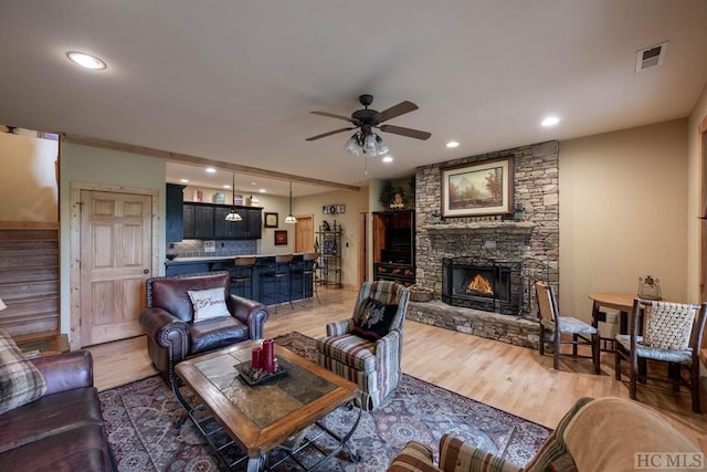 living room featuring ceiling fan, a fireplace, and wood-type flooring