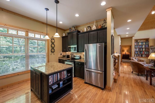 kitchen featuring appliances with stainless steel finishes, decorative light fixtures, light stone countertops, a center island, and light hardwood / wood-style floors