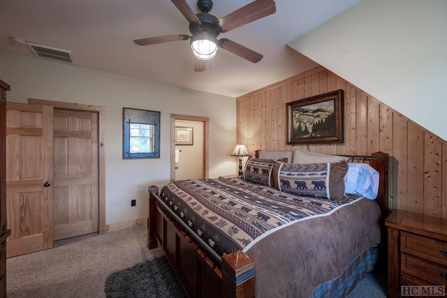 bedroom with carpet, wooden walls, and ceiling fan