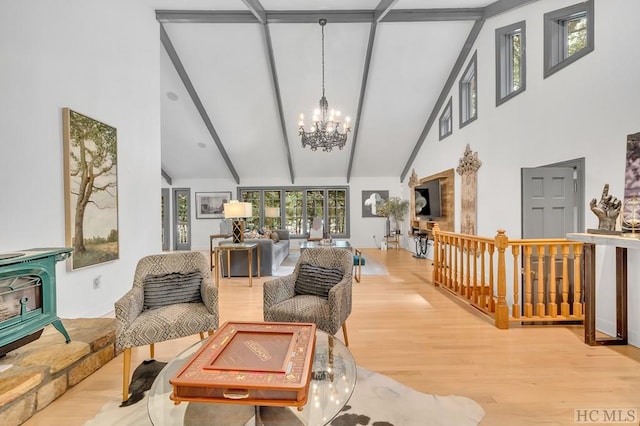 living area with hardwood / wood-style flooring, a wood stove, beamed ceiling, and a chandelier