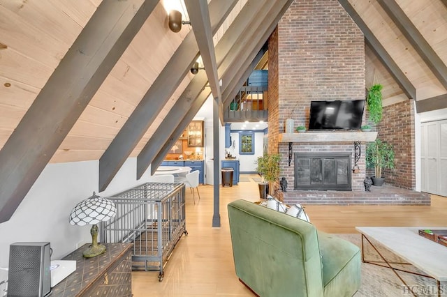 living room featuring light hardwood / wood-style flooring, vaulted ceiling with beams, and a brick fireplace