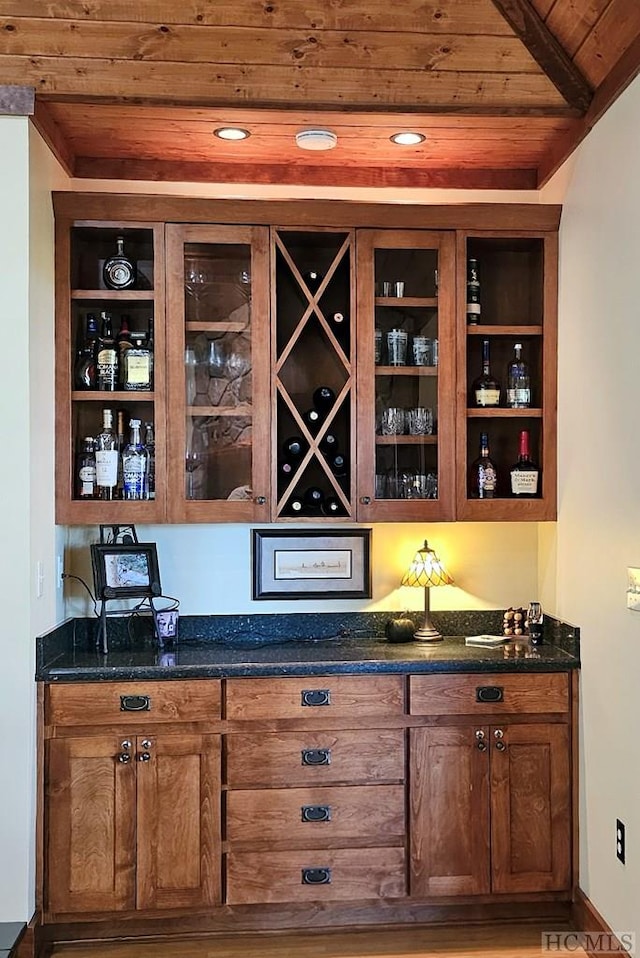 bar featuring dark stone countertops, wood ceiling, wood-type flooring, and lofted ceiling with beams