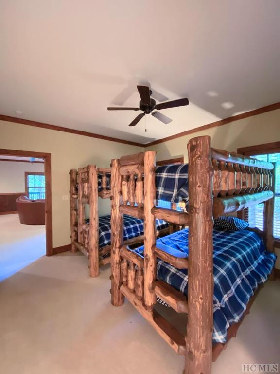 carpeted bedroom with ornamental molding and ceiling fan